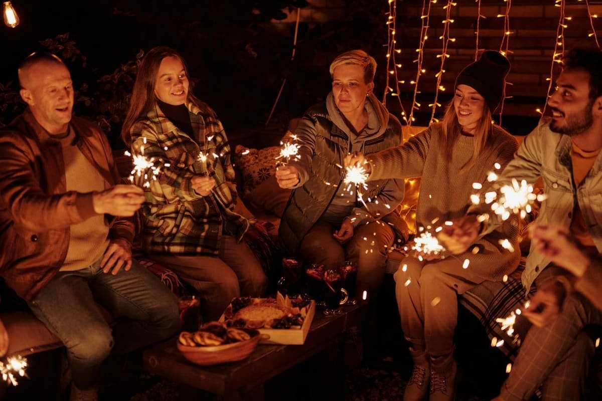 Table de fête éclairée à la nuit tombée, entourée d’amis